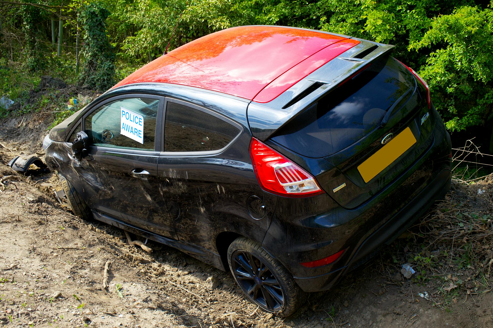 abandoned black car on dirt road