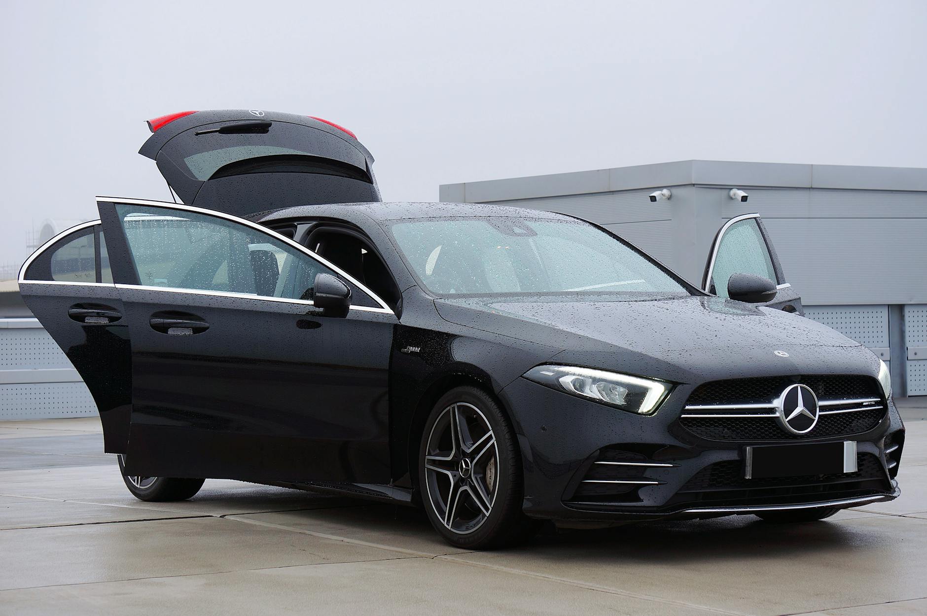 black mercedes benz with open doors on overcast day