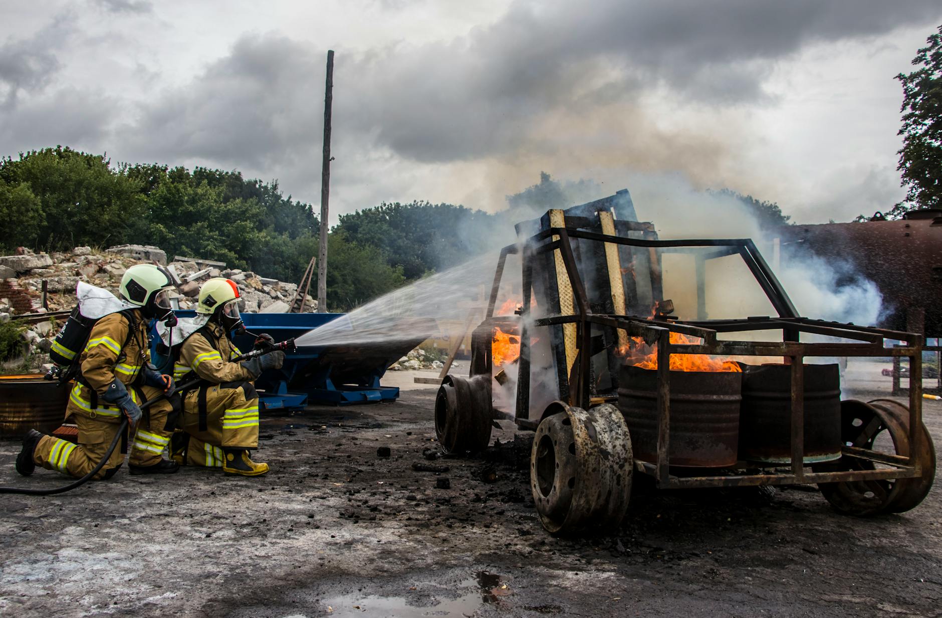 two firefighters extinguish a car